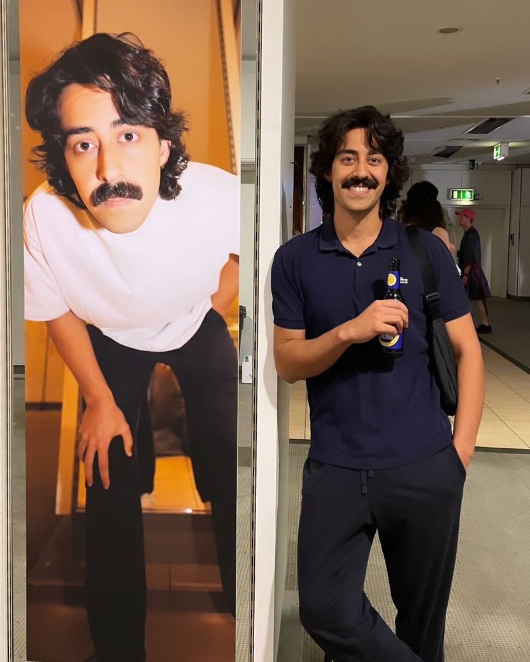 Mory Naimi standing next to a large poster of himself at 48 Hours Neukölln, Berlin.
