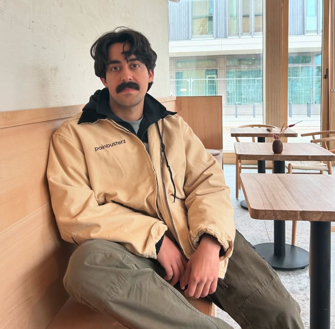 Mory Naimi wearing a Painbusterz jacket in an office during autumn.