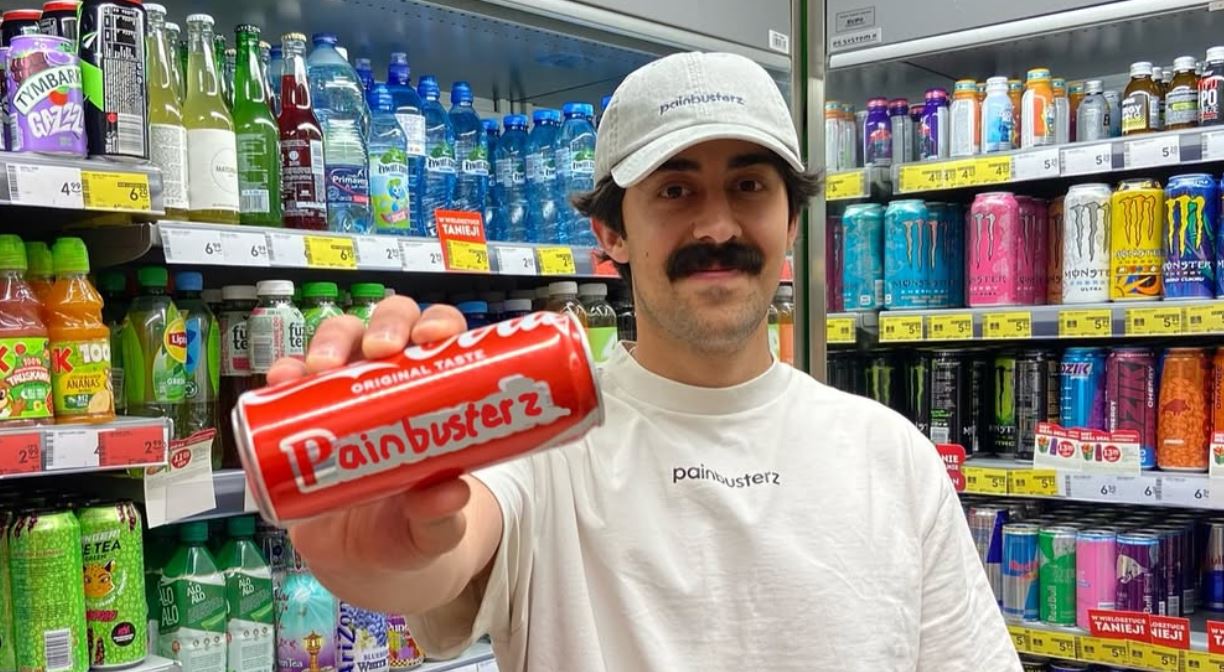 Mory Naimi holding a cola can edited with the Painbusterz logo, in Zabka.